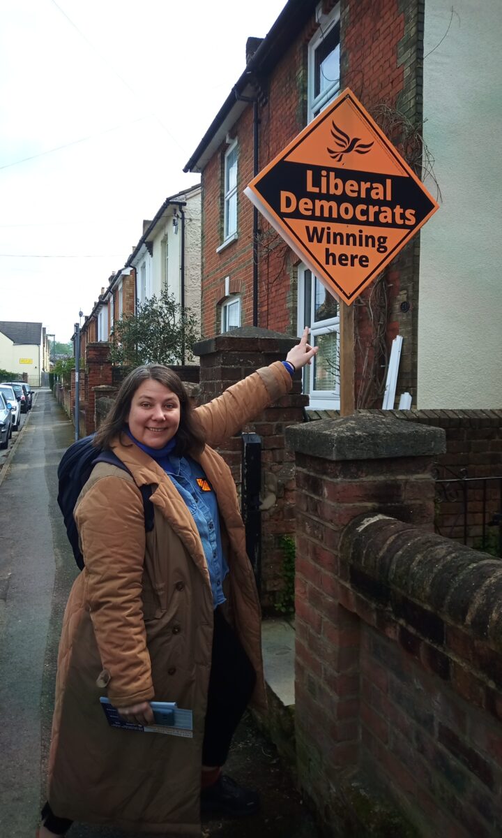 Sarah Lewis pointing at a Lib Dem poster
