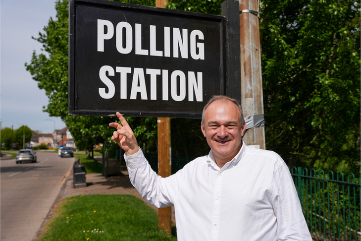 Ed Davey pointing at a polling station sign